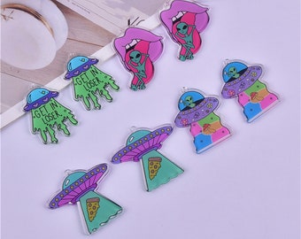 May include: Assortment of colorful plastic charms featuring alien and UFO designs. Some charms have the text "Get in Loser" printed on them.