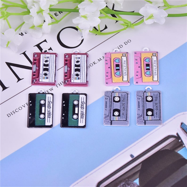May include: Eight colorful cassette tape charms with different designs. The charms feature a variety of colors, including pink, yellow, green, black, and gray. The charms are perfect for adding a retro touch to jewelry, keychains, or other crafts.