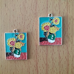 May include: Two metal charms featuring a painting of sunflowers in a vase. The charms are rectangular and have a turquoise background with red and yellow accents.