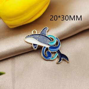 May include: Gold-tone metal charm featuring a blue and white dolphin with a blue and turquoise swirl design. The charm measures 20 x 30 mm.