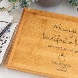 Pode incluir: Uma bandeja de caf&eacute; da manh&atilde; retangular de bambu com texto gravado. O texto diz "Mummy's breakfast in b" com texto adicional e um gr&aacute;fico de x&iacute;cara de caf&eacute;. Um jornal e uma caneta s&atilde;o vis&iacute;veis &agrave; esquerda.