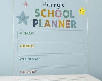 May include: A clear acrylic school planner with the text "Harry's SCHOOL PLANNER" in colorful letters. The planner has sections for each weekday and notes, decorated with star illustrations.
