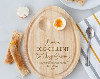May include: A wooden egg-shaped serving tray with two egg cups. The tray has the text "Have an EGG-CELLENT Birthday Sammy HOPE IT'S EGGS-TRA GOOD Lots of love Billy" engraved on it.