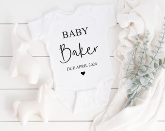 May include: White baby onesie with black text that reads "BABY Baker DUE APRIL 2024" with a small black heart.