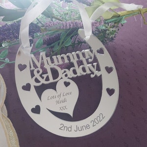 Pu&ograve; includere: Ciondolo bianco a forma di ferro di cavallo con le parole "Mummy & Daddy" e un cuore con il testo "Lots of Love Heidi xxx" e la data "2nd June 2022".