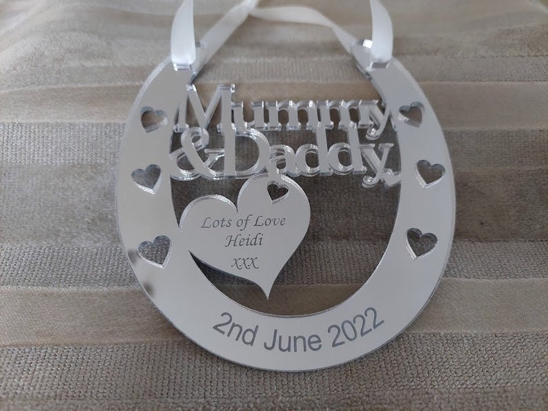 Pu&ograve; includere: Ciondolo a forma di ferro di cavallo in specchio argentato con il testo "Mummy & Daddy" e un cuore con il testo "Lots of Love Heidi xx" e la data "2nd June 2022".