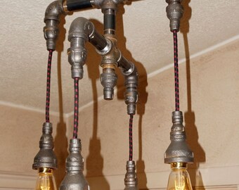 May include: A five-light industrial style chandelier made from black metal pipes with red and black electrical cords. The chandelier has a circular metal ceiling plate and five exposed light bulbs.
