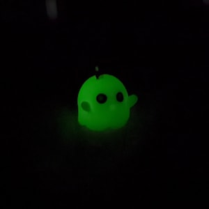 Op de afbeelding: Een klein, groen, glow-in-the-dark spookfiguurtje met zwarte ogen.