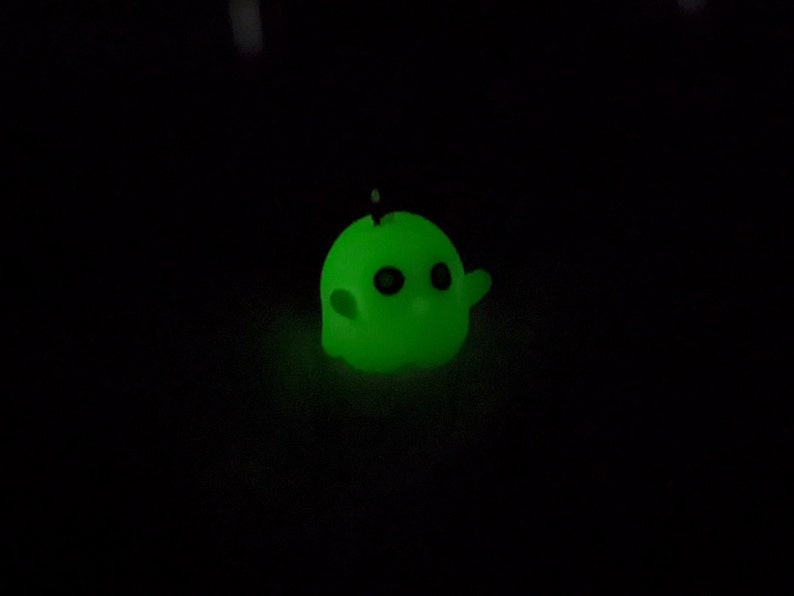 Op de afbeelding: Een klein, groen, glow-in-the-dark spookfiguurtje met zwarte ogen.