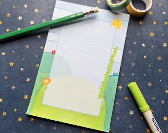 May include: A blank notepad with a green, blue, and yellow cartoon design. The notepad is on a blue background with gold stars. There is a green pencil, a yellow eraser, and a green highlighter on the notepad.