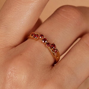 May include: A gold ring with a row of small red gemstones.