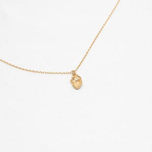 May include: A gold chain necklace with a small, detailed heart pendant.