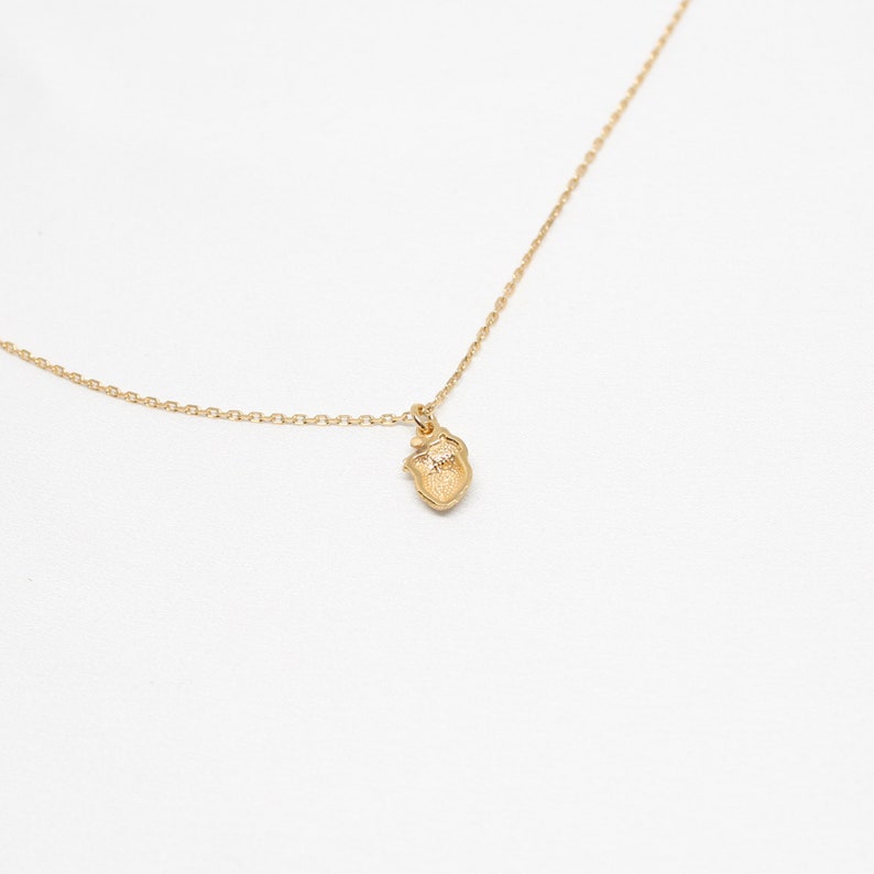 May include: A gold chain necklace with a small, detailed heart pendant.