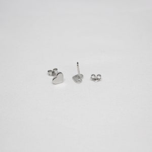以下が含まれることがあります： シルバーのハート型のスタッドピアスのペア。ピアスは小さく繊細で、シンプルでエレガントなデザインです。