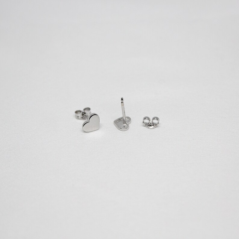 以下が含まれることがあります： シルバーのハート型のスタッドピアスのペア。ピアスは小さく繊細で、シンプルでエレガントなデザインです。