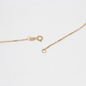 May include: A gold chain necklace with a lobster clasp and a jump ring. The chain is made of small, delicate links.