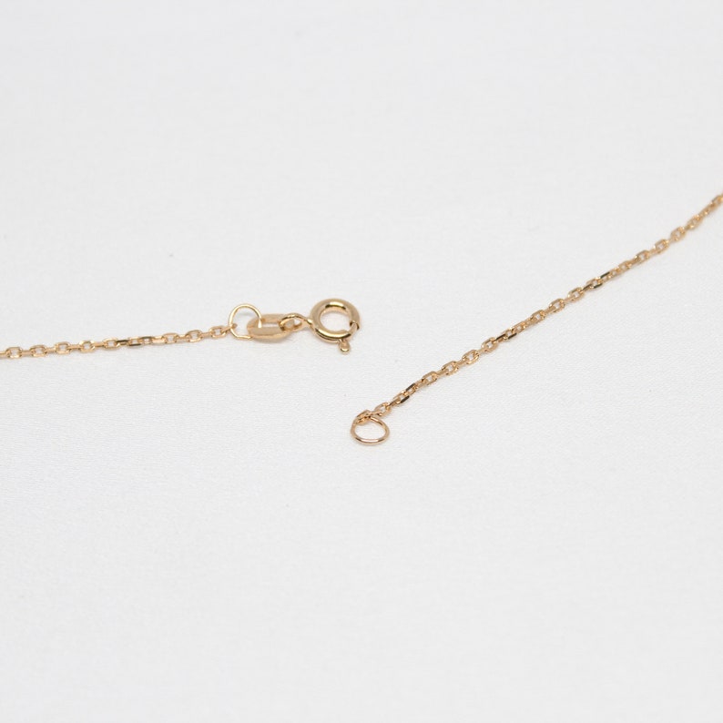 May include: A gold chain necklace with a lobster clasp and a jump ring. The chain is made of small, delicate links.