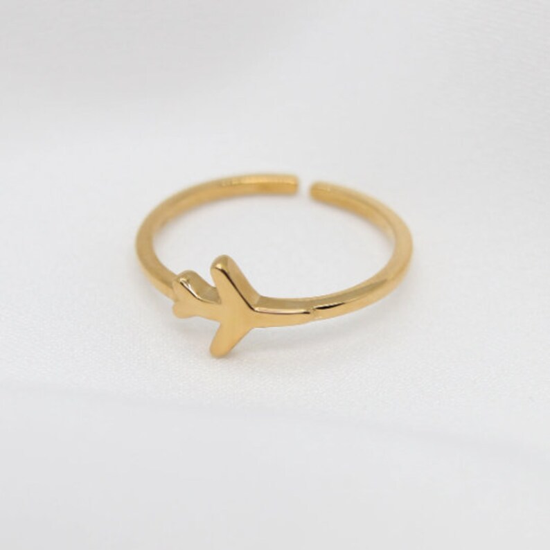 Op de afbeelding: Een gouden vliegtuigring. De ring is simpel en delicaat, met een klein vliegtuigontwerp.