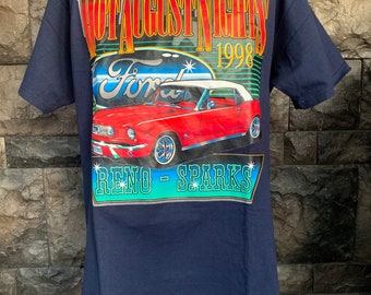 Op de afbeelding: Een marineblauw t-shirt met een grafische print van een rode Ford Mustang cabriolet. De grafiek bevat de tekst "Hot August Nights 1998" en "Reno - Sparks".