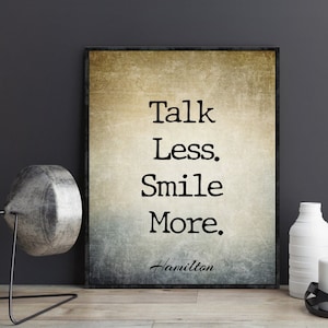 Peut inclure: Une impression de style vintage avec une citation motivante : « Parlez moins. Souriez plus. » La citation est attribuée à Hamilton.