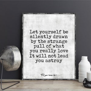May include: Black and white typography quote on a white background with a gray texture. The quote reads "Let yourself be silently drawn by the strange pull of what you really love. It will not lead you astray." The quote is attributed to Rumi.