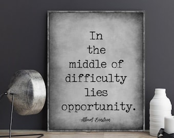 May include: Black and white typography print with the quote "In the middle of difficulty lies opportunity." attributed to Albert Einstein. The print has a textured background.