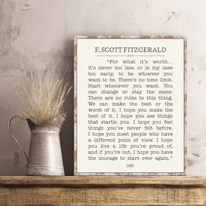 May include: A framed print with a beige background and black text. The quote is by F. Scott Fitzgerald and is about living life to the fullest and starting over. The quote reads, "For what it's worth... it's never too late, or in my case too early, to be whoever you want to be. There's no time limit. Start whenever you want. You can change or stay the same. There are no rules to this thing. We can make the best or the worst of it. I hope you make the best of it. I hope you see things that startle you. I hope you feel things you've never felt before. I hope you meet people who have a different point of view. I hope you live a life you're proud of, and if you're not, I hope you have the courage to start over again." The quote is followed by the number 198.