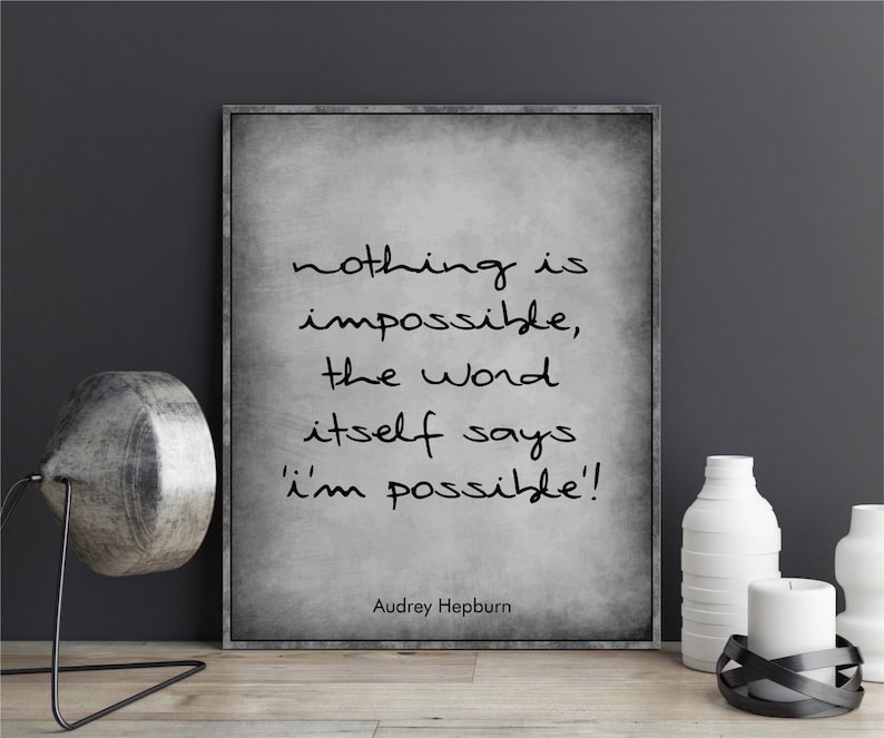 May include: A black and white inspirational quote print with a gray textured background. The quote reads "nothing is impossible, the word itself says 'i'm possible!'". The quote is attributed to Audrey Hepburn.