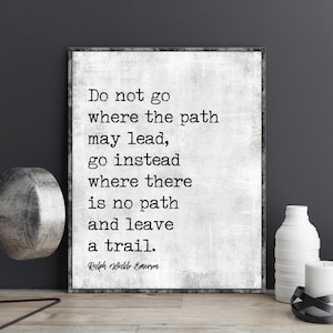 Op de afbeelding: Een zwart-wit typografieprint met een citaat van Ralph Waldo Emerson: "Ga niet waar het pad leidt, ga in plaats daarvan waar geen pad is en laat een spoor achter."