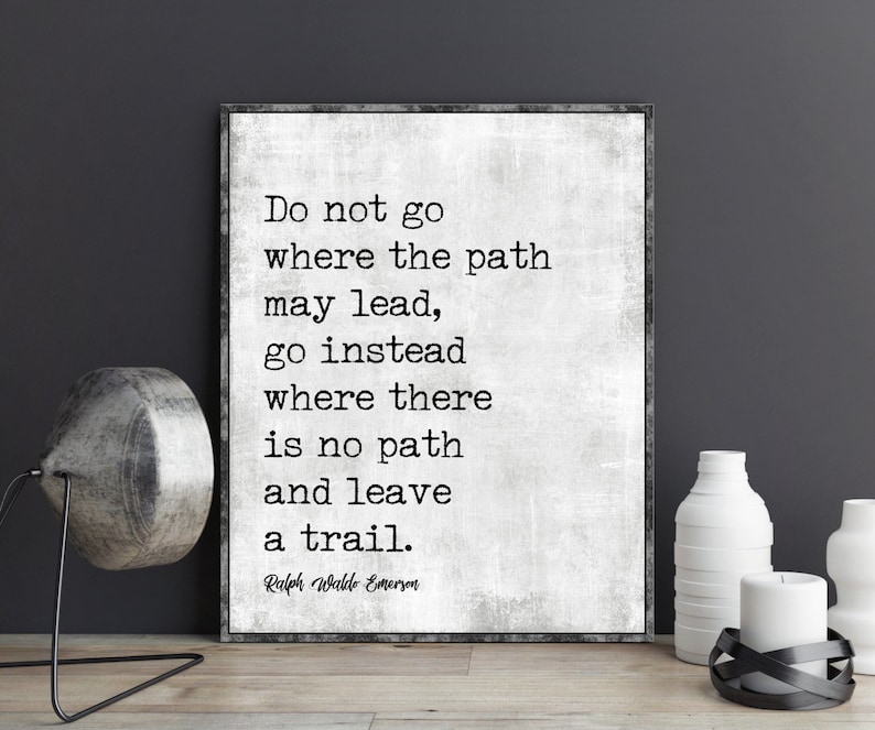 Op de afbeelding: Een zwart-wit typografieprint met een citaat van Ralph Waldo Emerson: "Ga niet waar het pad leidt, ga in plaats daarvan waar geen pad is en laat een spoor achter."