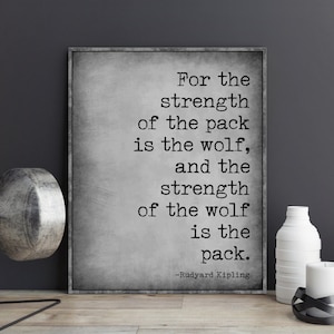 May include: A black and white typography print with a quote by Rudyard Kipling: "For the strength of the pack is the wolf, and the strength of the wolf is the pack."