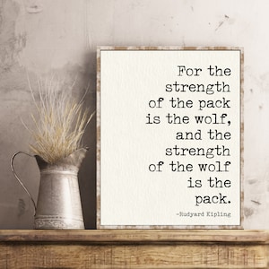 May include: A white framed print with a quote by Rudyard Kipling: "For the strength of the pack is the wolf, and the strength of the wolf is the pack."