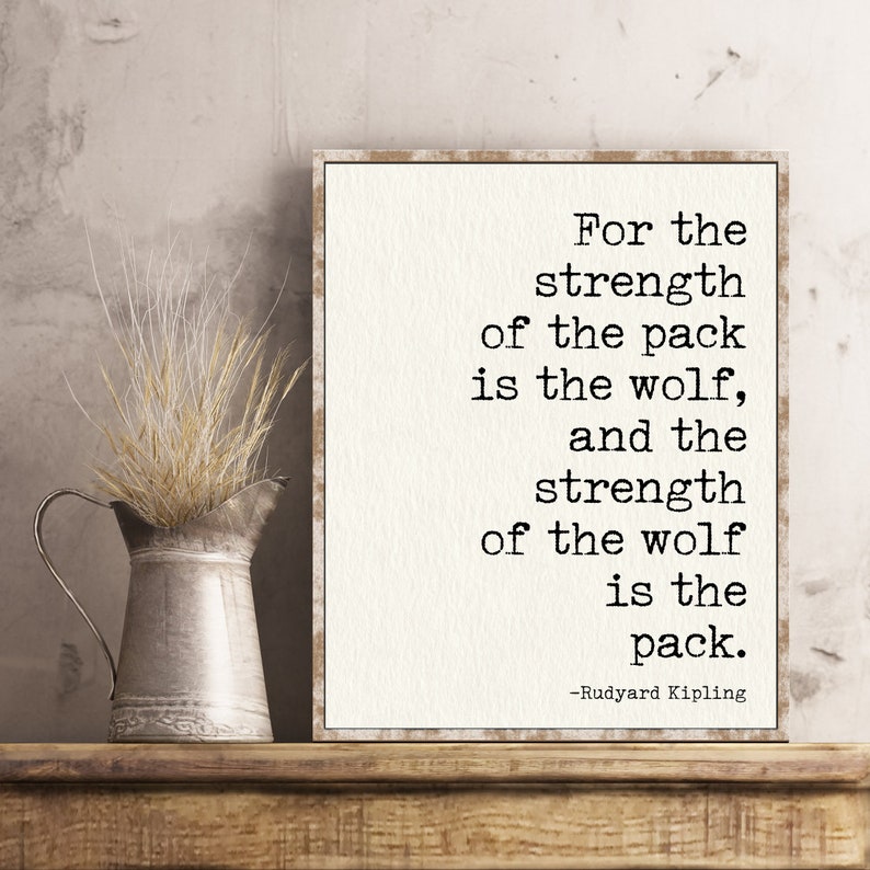 May include: A white framed print with a quote by Rudyard Kipling: "For the strength of the pack is the wolf, and the strength of the wolf is the pack."