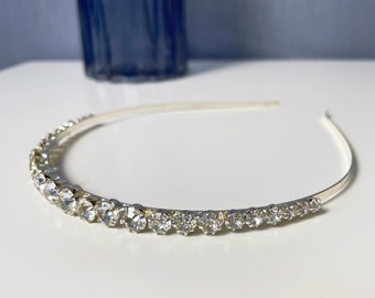 May include: A silver headband with a row of clear rhinestones.