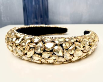 May include: A gold headband with a wide band of teardrop-shaped rhinestones.