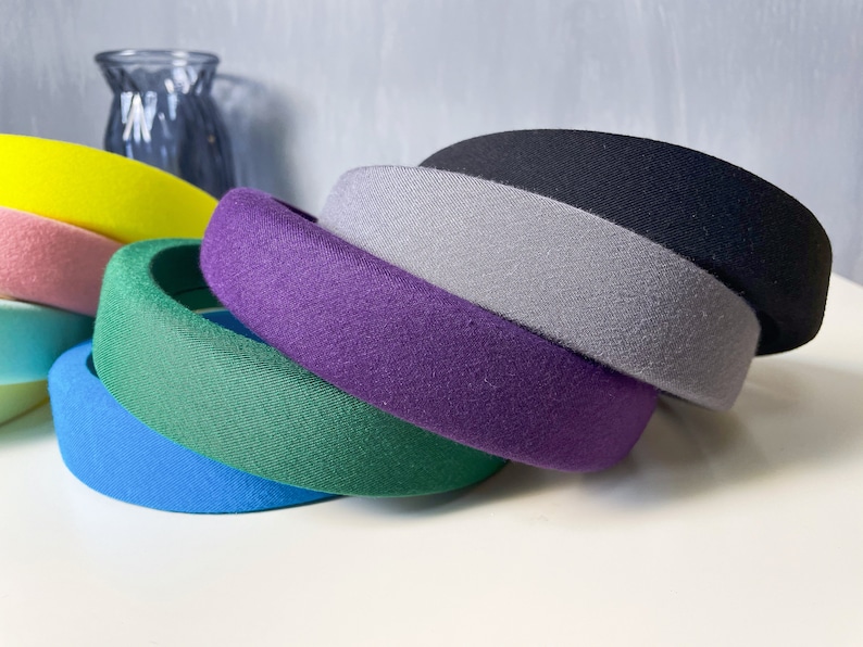 May include: A set of six colorful fabric headbands in various shades of blue, green, purple, gray, pink, and yellow. The headbands are made of a soft, stretchy fabric and are designed to be comfortable to wear.