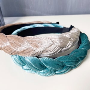 May include: Two braided velvet headbands, one in a light beige color and the other in a teal blue color.