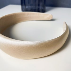 K&ouml;nnte beinhalten: Ein breites, cremefarbenes Satin-Haarband.