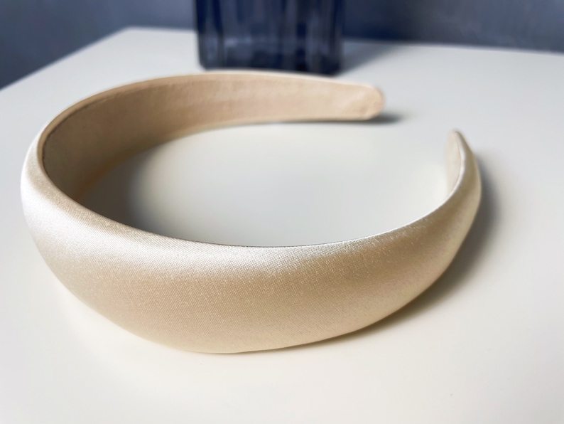 K&ouml;nnte beinhalten: Ein breites, cremefarbenes Satin-Haarband.