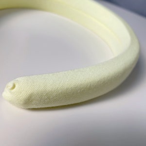 May include: A pale yellow headband made of soft fabric.