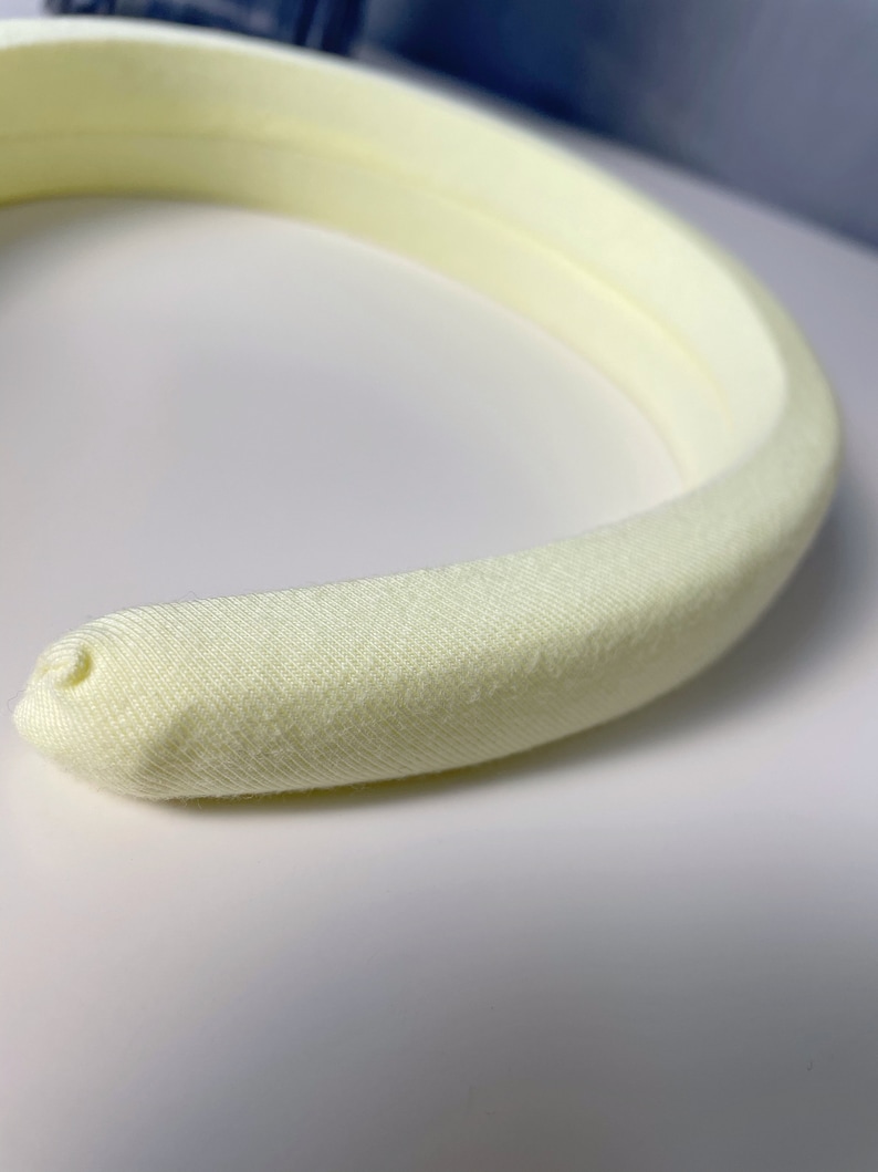 May include: A pale yellow headband made of soft fabric.