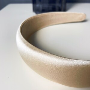 K&ouml;nnte beinhalten: Ein breites, cremefarbenes Satin-Haarband.