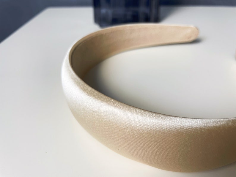 K&ouml;nnte beinhalten: Ein breites, cremefarbenes Satin-Haarband.