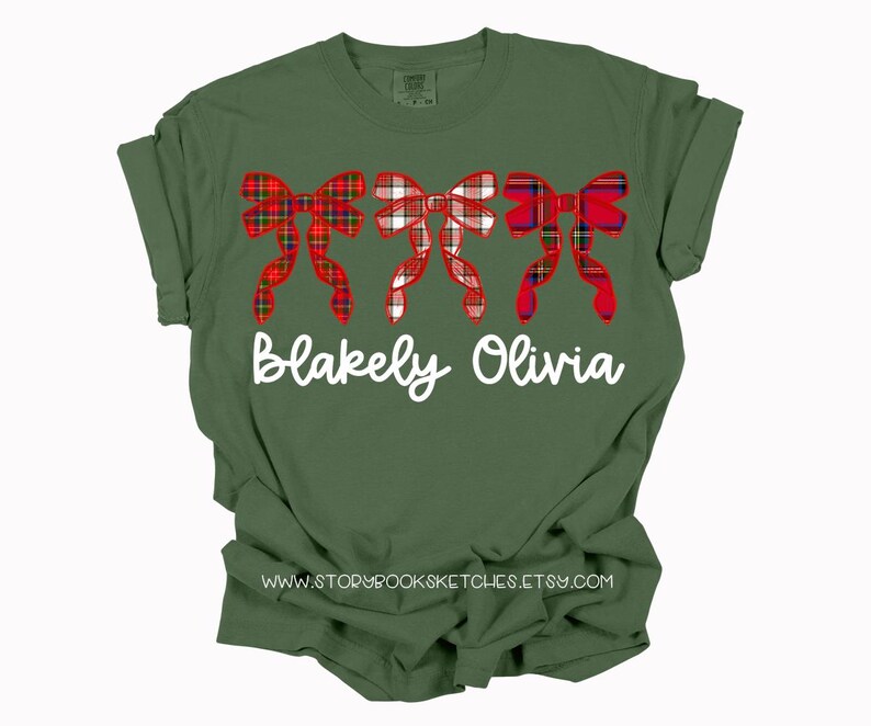 May include: A green t-shirt with a red and white plaid bow design and the names "Blakely Olivia" printed in white.