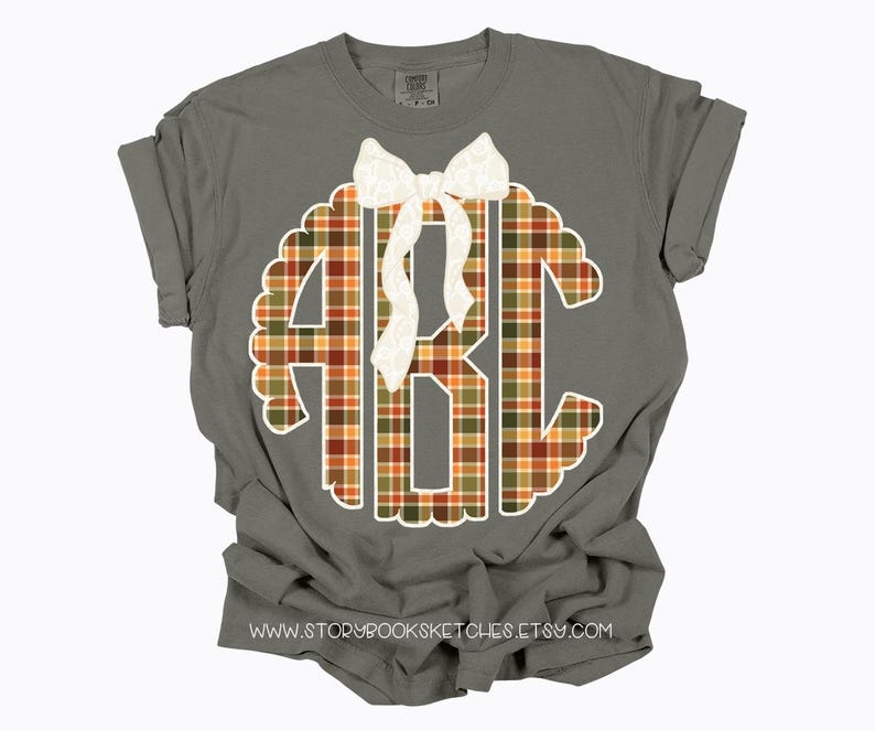 Puede incluir: Camiseta gris con mangas enrolladas con un monograma festoneado blanco con las letras ABC en un patr&oacute;n de cuadros. Un lazo blanco est&aacute; centrado encima del monograma. La direcci&oacute;n del sitio web www.storybooksketches.etsy.com est&aacute; impresa en la parte inferior.