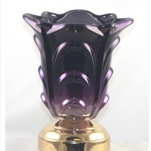 May include: A purple glass oil burner with a gold base. The burner has a flower-shaped design and a gradient of color from dark purple to light purple.
