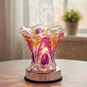 May include: A decorative glass essential oil diffuser with a vibrant pink, yellow, and purple floral design. The diffuser sits on a silver base and emits a gentle stream of vapor. The warm light from the candle inside illuminates the colorful glass.