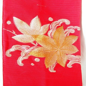 Leuchtend roter Nagoya Obi für den Sommer - goldene und silberne Ahornblätter über einem Bach