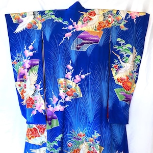 May include: A blue silk kimono with a traditional Japanese design featuring cranes, flowers, and gold accents.