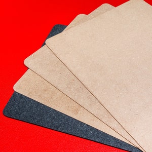 May include: Four pieces of sandpaper in different grits, arranged in a fan shape on a red background. The sandpaper is beige and black.